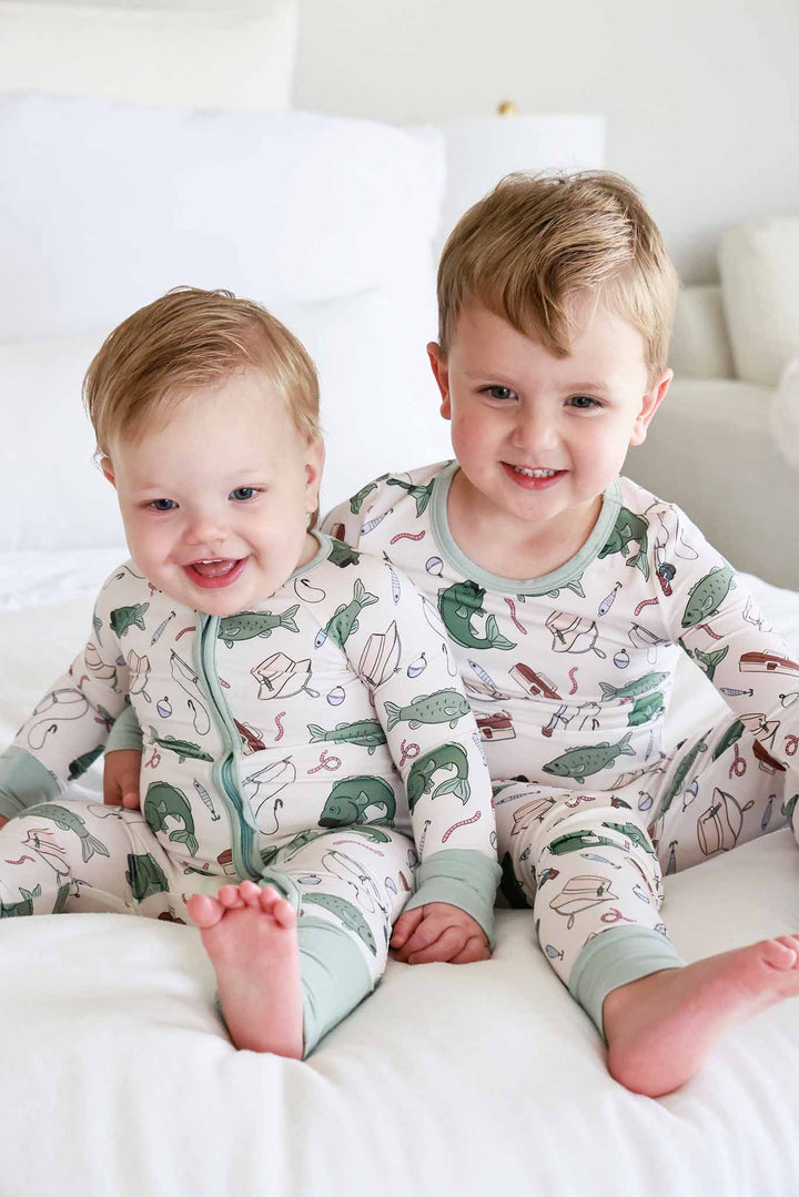 Two brothers wearing the Off The Hook convertible zip romper and two piece pajama set with fishing print