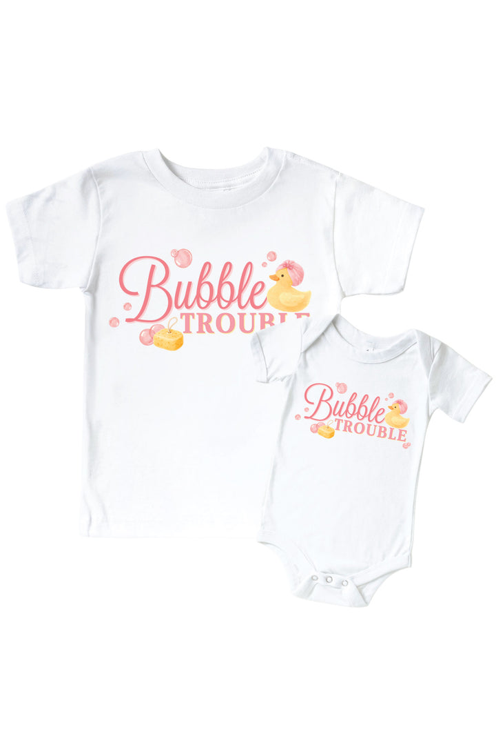 White kids tee and baby bodysuit with pink Bubble Trouble cursive text graphic and yellow rubber duck with pink bubbles