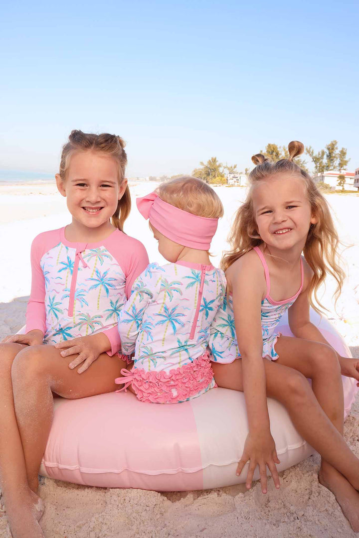 sisters wearing matching neon palm tree swimsuits at the beach 
