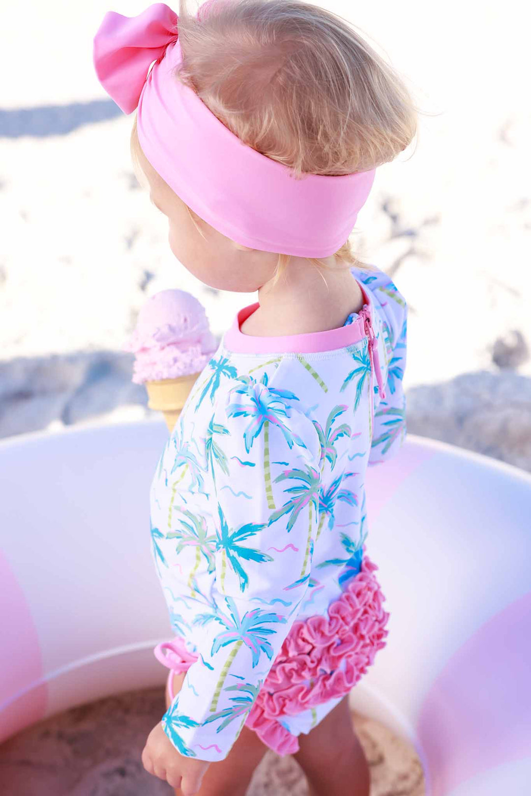 side view of blue lagoon long sleeve rash guard with pink ruffle bottom and matching pink headwrap 