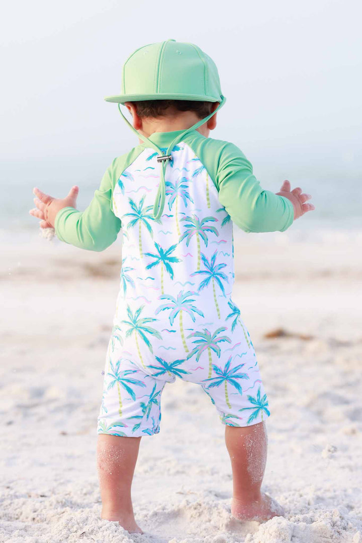 boy walking on sand at the beach in blue lagoon rash guard shortie romper 
