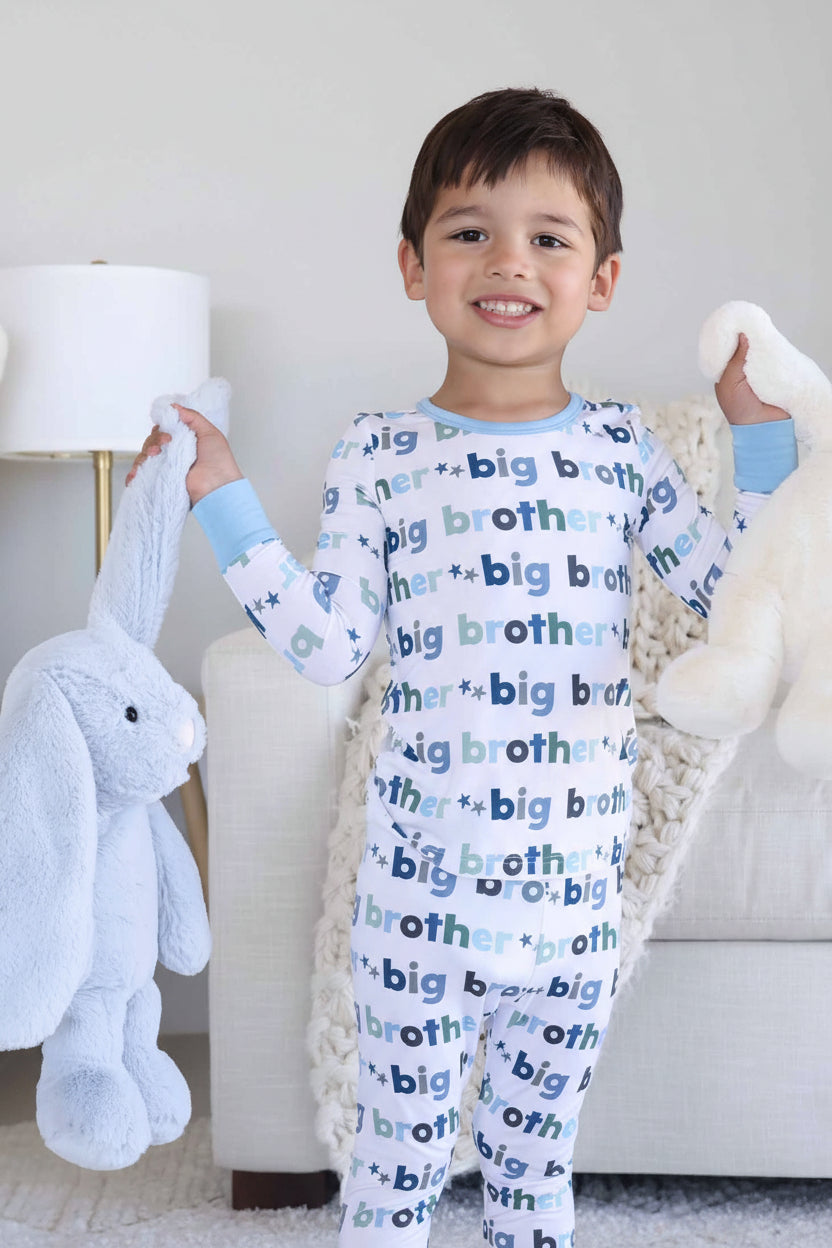 boy in big brother pajama two piece set holding light blue and white bunny stuffed animals 