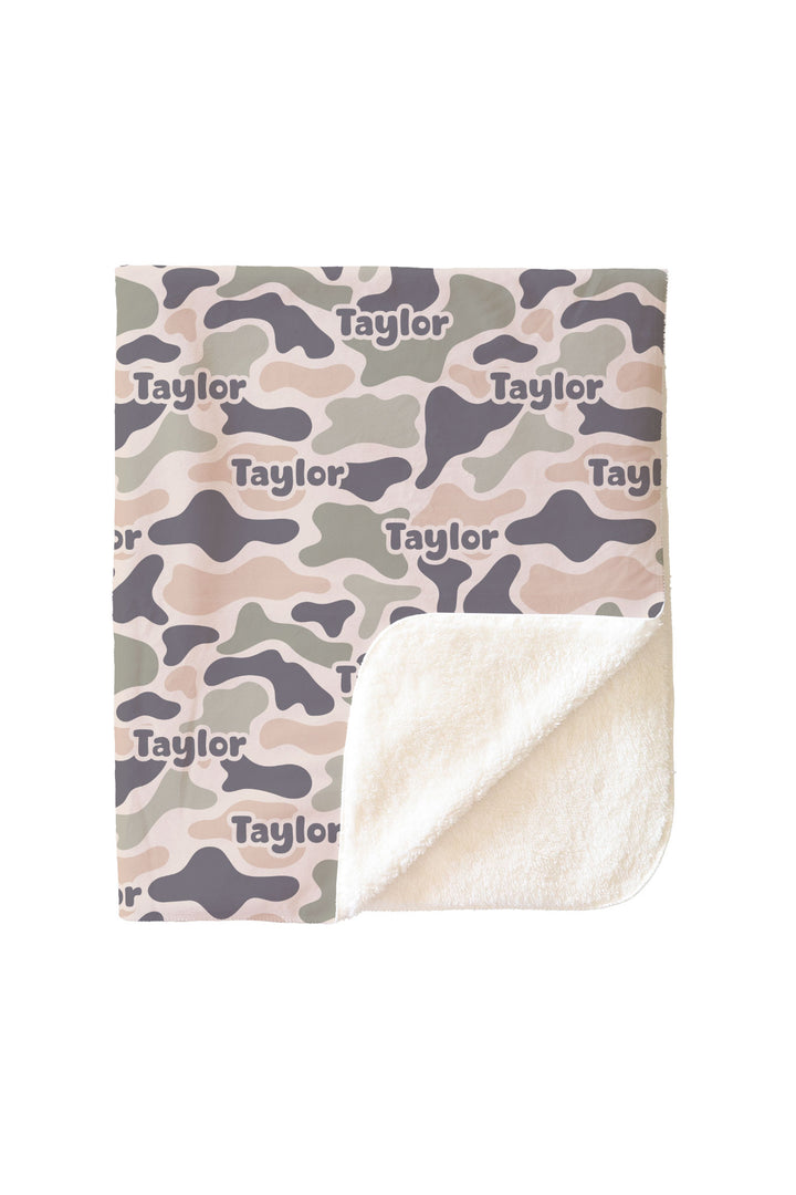 Personalized camo cutie kids blanket with corner folded back showing soft white sherpa interior and camo print exterior with custom name