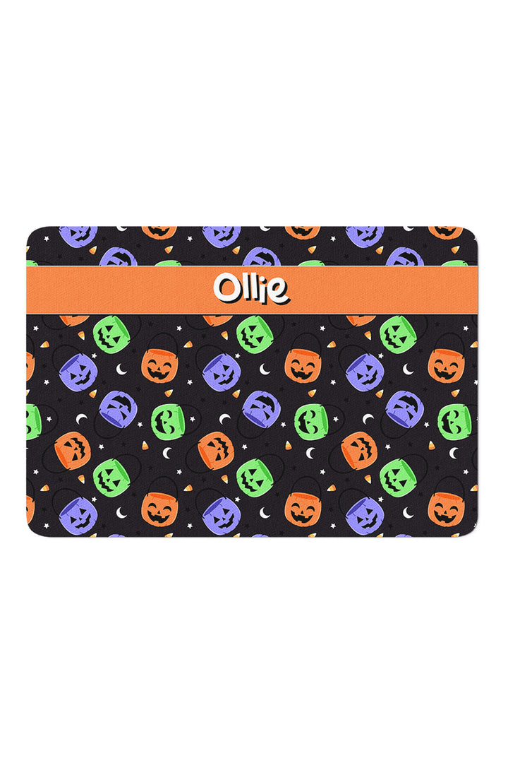 Personalized Halloween pet placemat with black jack-o-lantern and candy corn print and an orange band customized with the name Ollie