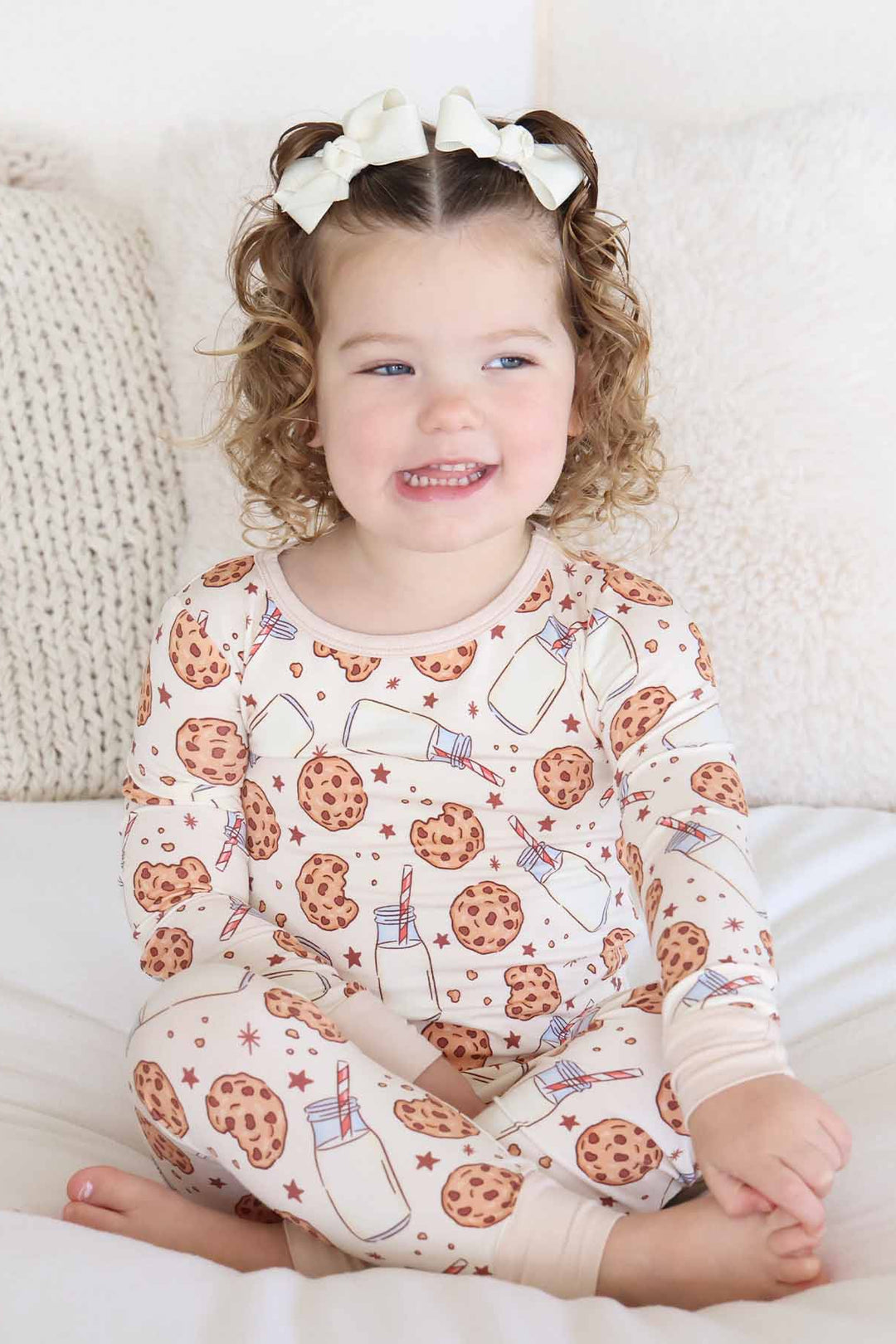 girl sitting on a bed wearing cookie cuddles pajama 