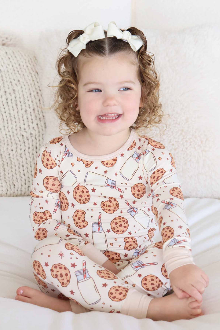 girl sitting on a bed wearing cookie cuddles pajama 