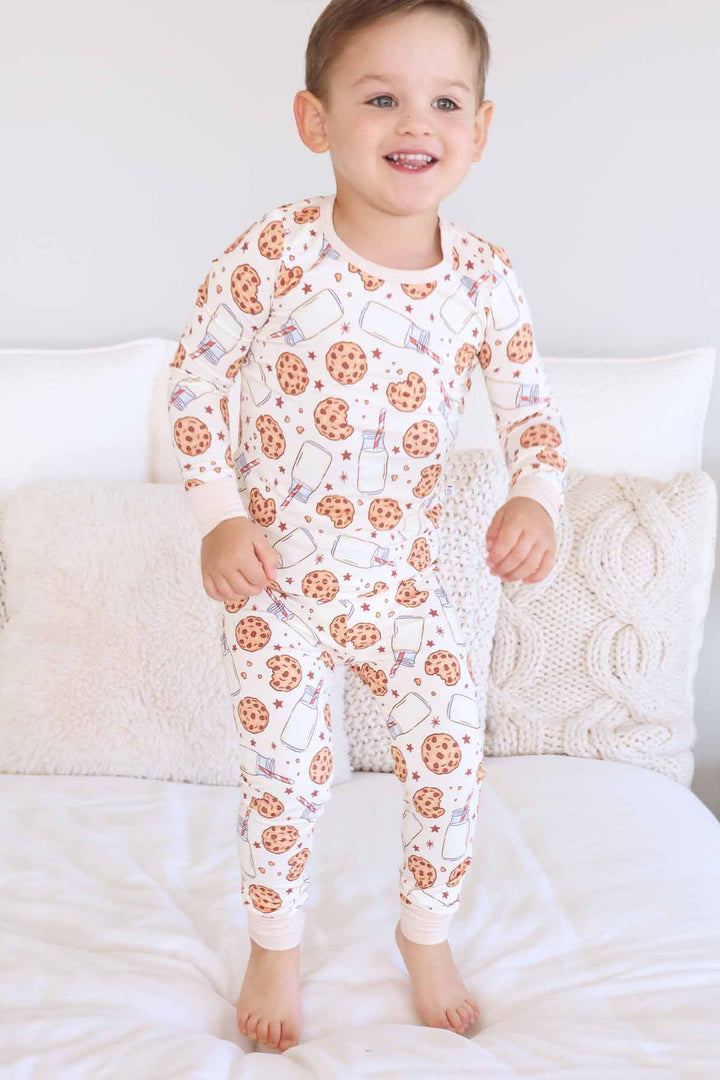 boy jumping on a bed wearing milk and cookies two piece pajama set 