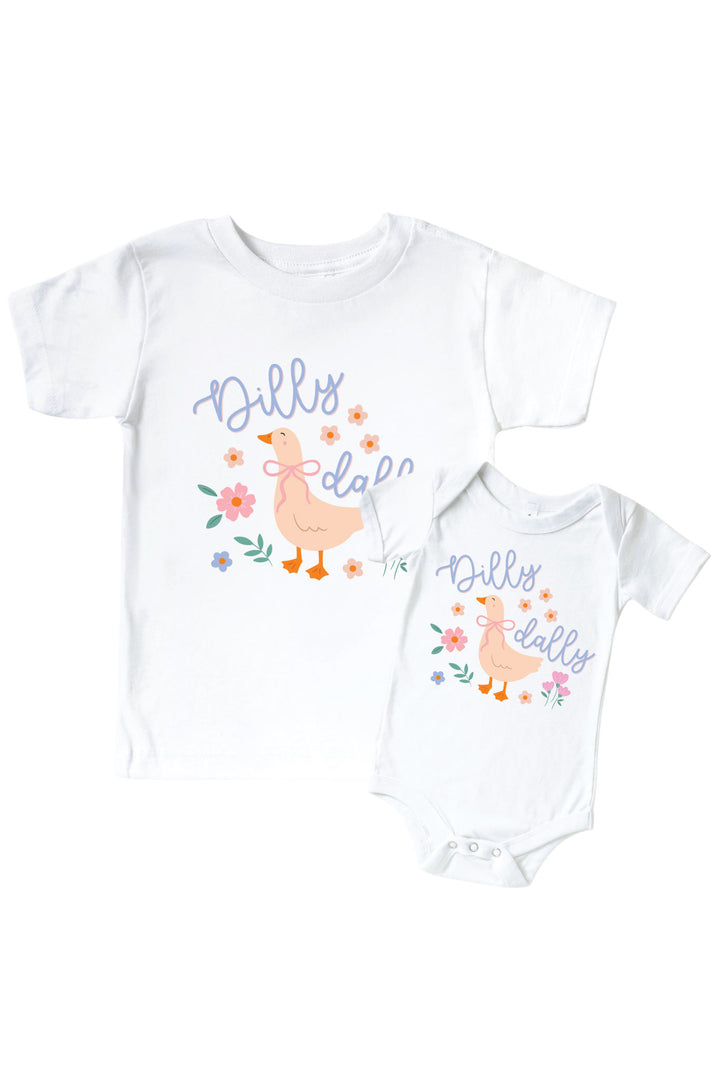 White kids tee and baby bodysuit mockup with Dilly Dally graphic featuring a goose with flowers and script text, showing both sizes on a white background