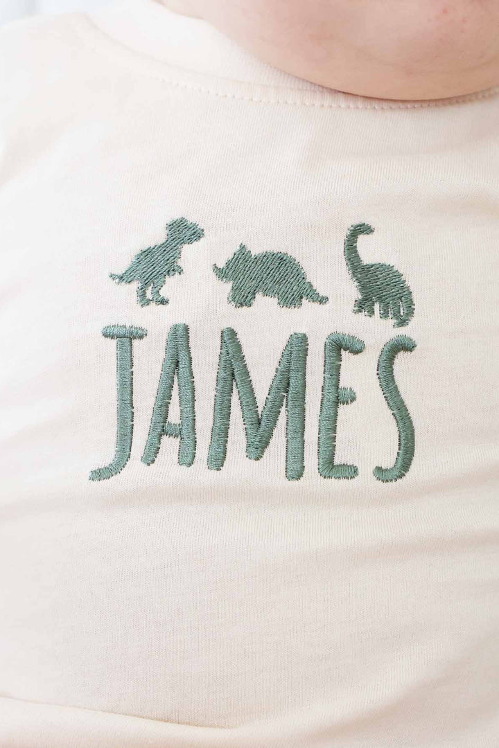 natural tan green thread dinosaur and name embroidered long sleeve bubble romper for babies and toddlers