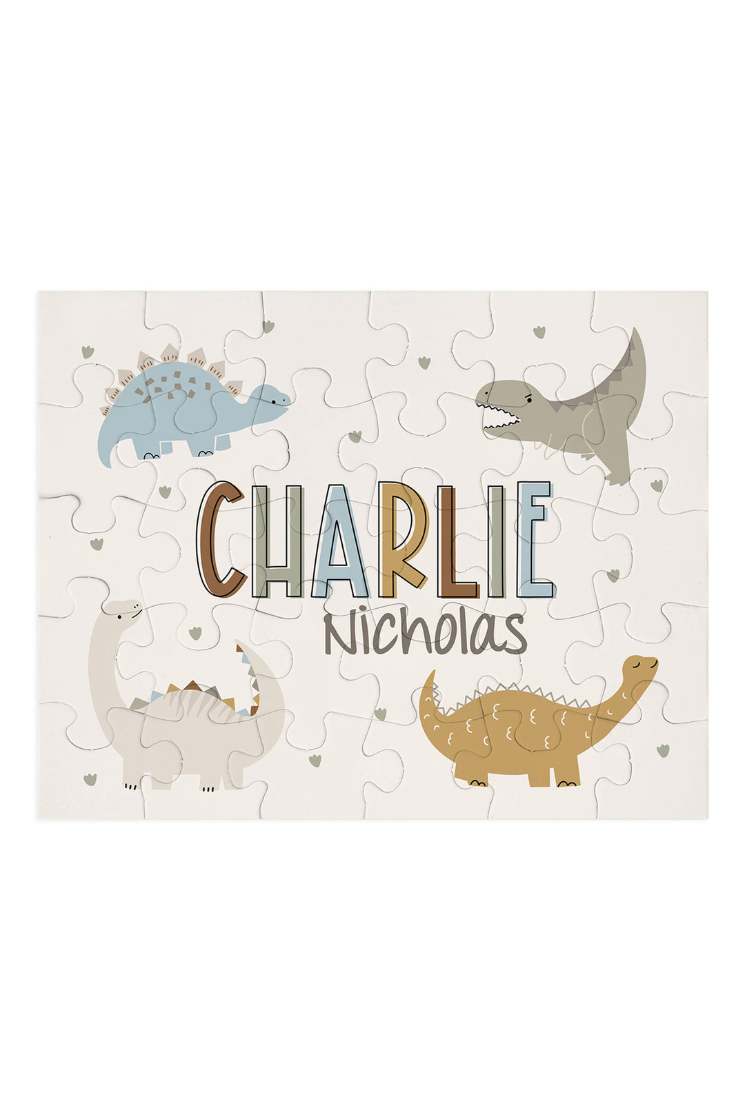 Flat lay of an assembled personalized Caden Lane Dino Stomps jigsaw puzzle in cream, showing dinosaurs and custom name