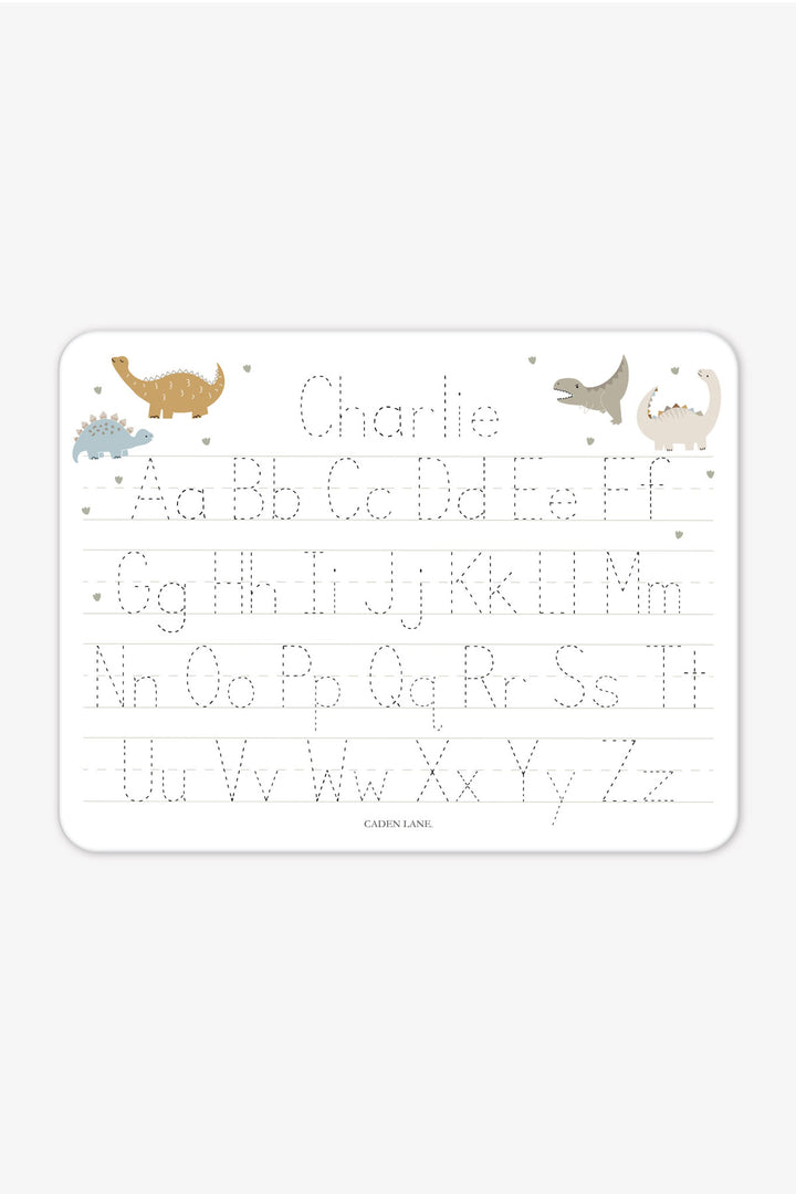 Flat lay of a personalized Caden Lane Dino Stomps alphabet whiteboard, showing dinosaurs and tracing letters with custom name