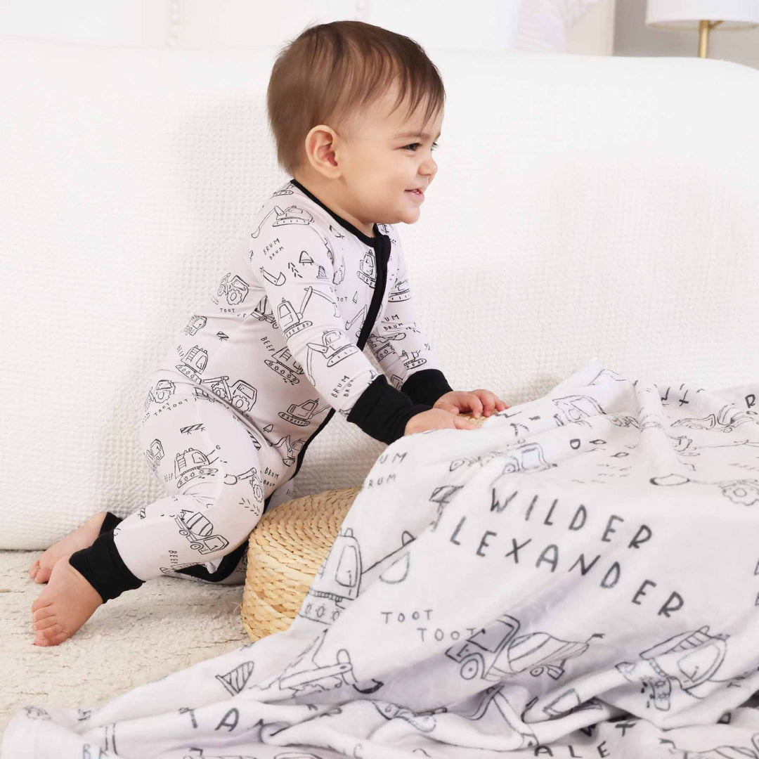 boy with personalized graphic blanket in construction truck  and bulldozer doodle print and matching printed sleep romper