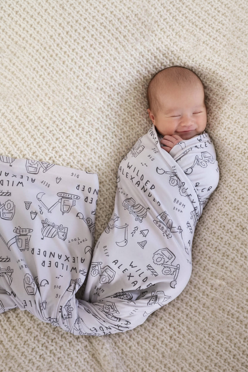 personalized and printed baby swaddle with doodles of construction trucks and dozers for boys