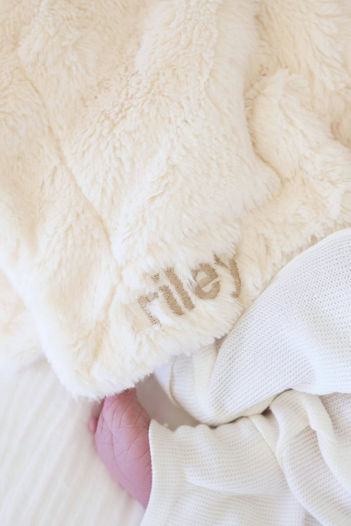 closeup of white bunny lovey for babies embroidered with name in neutral thread and block font 