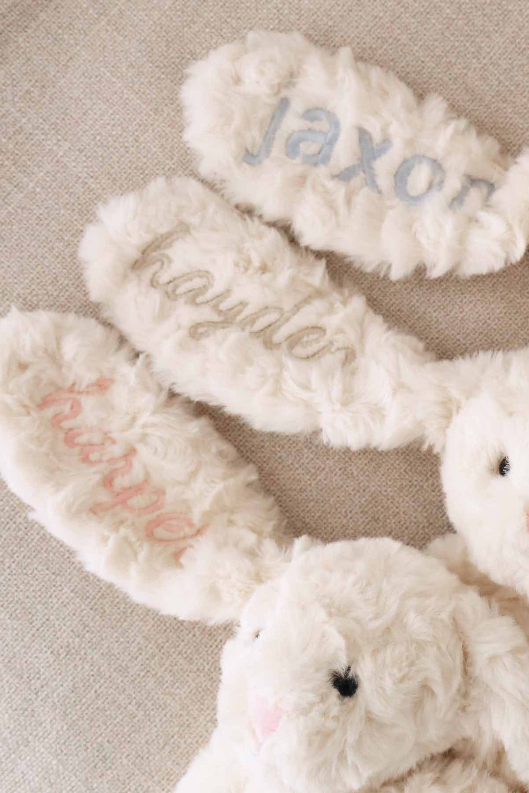 3 personalized stuffed animal bunnies with names embroidered on them in block and script fonts