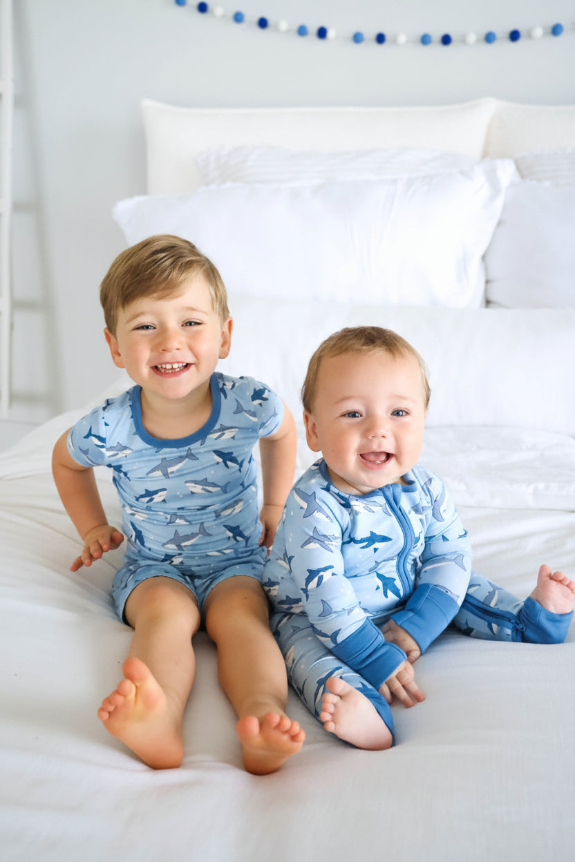 brothers sitting on bed in matching shark pajamas