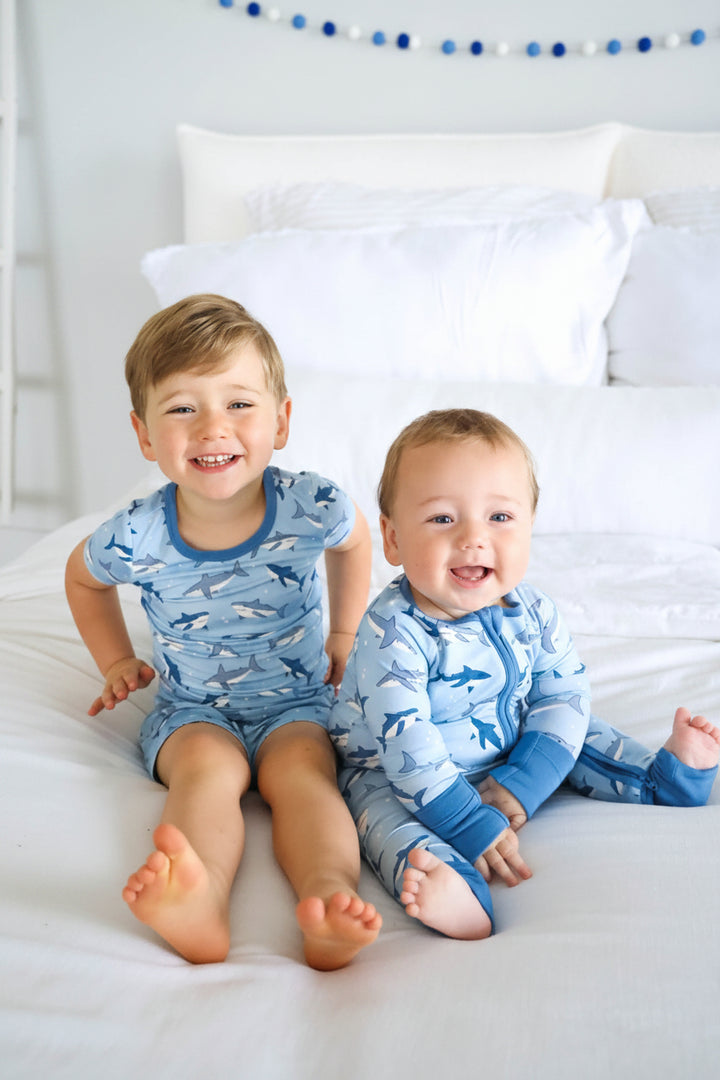 brothers sitting on bed in matching shark pajamas