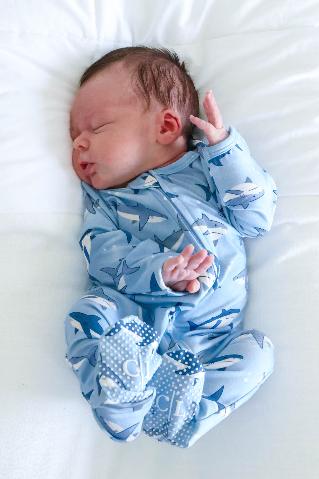 baby boy in bassinet wearing fin friends shark footie
