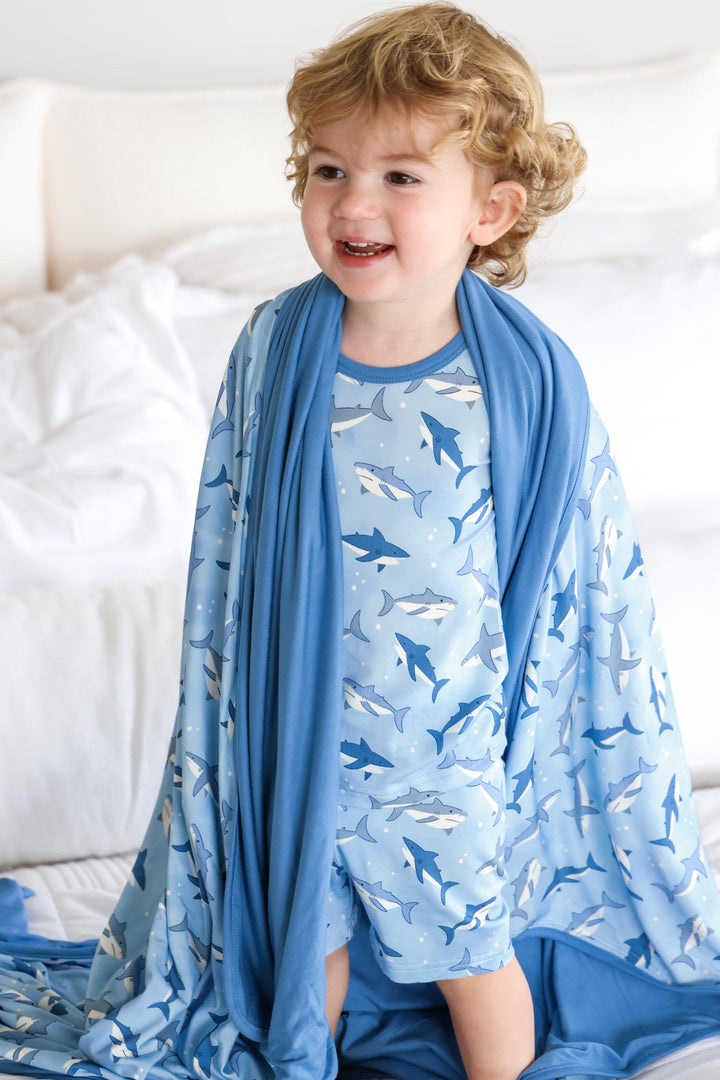 boy in shark pajamas with matching blanket around his shoulders