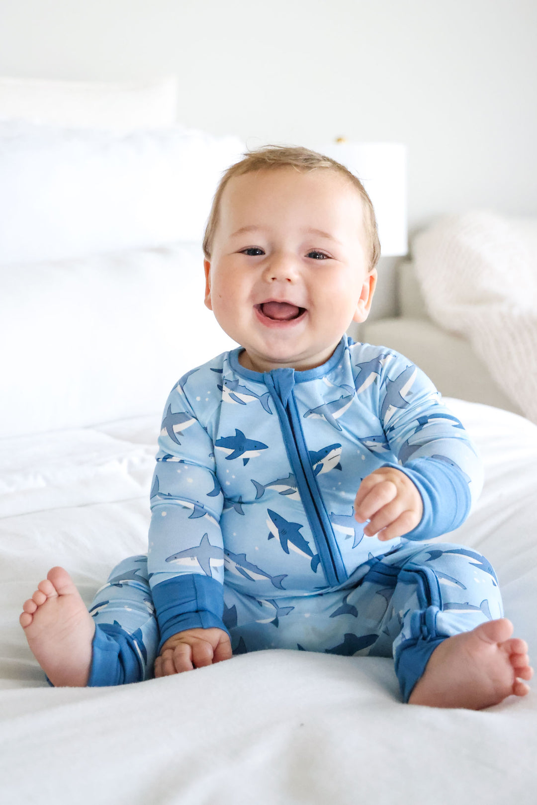 baby boy sitting on bed in shark convertible zip romper
