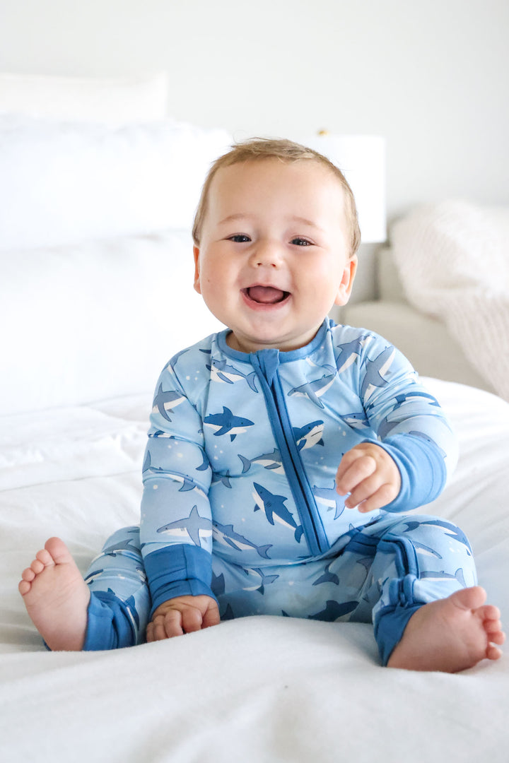 baby boy sitting on bed in shark convertible zip romper