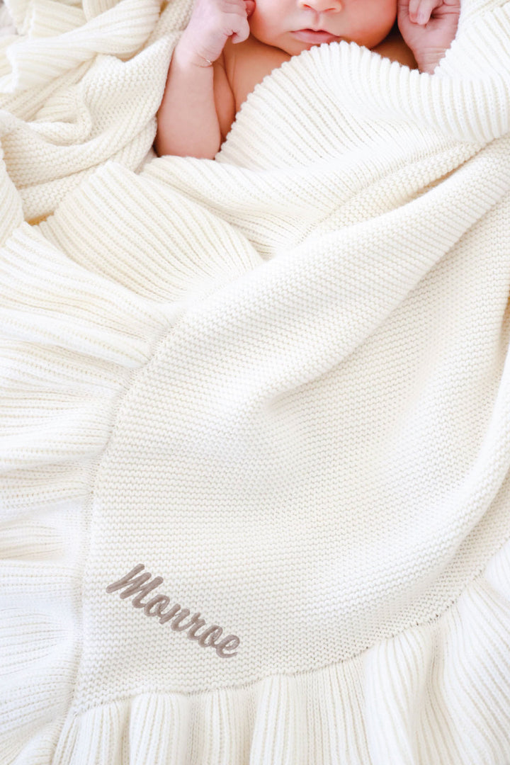 closeup of ivory ruffle blanket with embroidered name