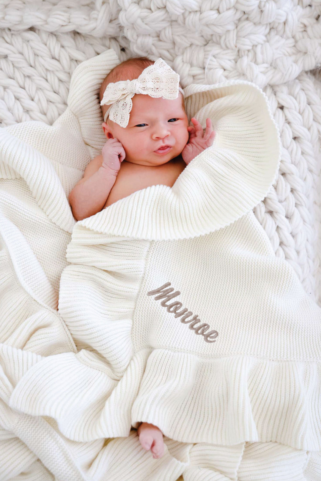 baby girl wrapped in ivory knit ruffle blanket with embroidered name in script font