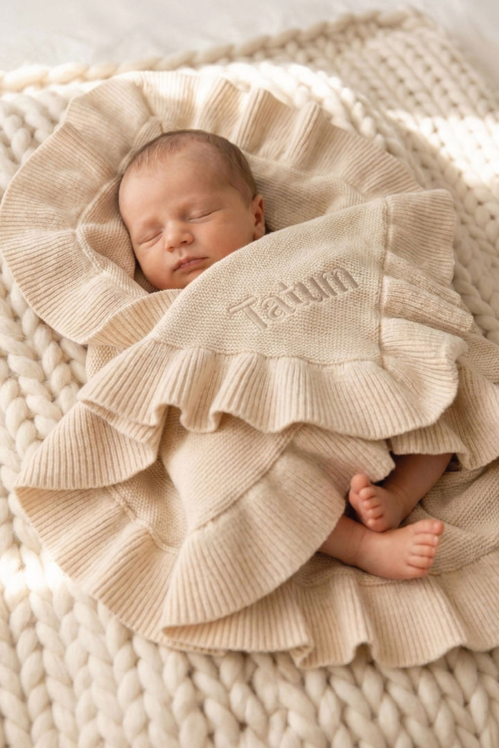 baby wrapped up in sand ruffle knit blanket with name embroidered