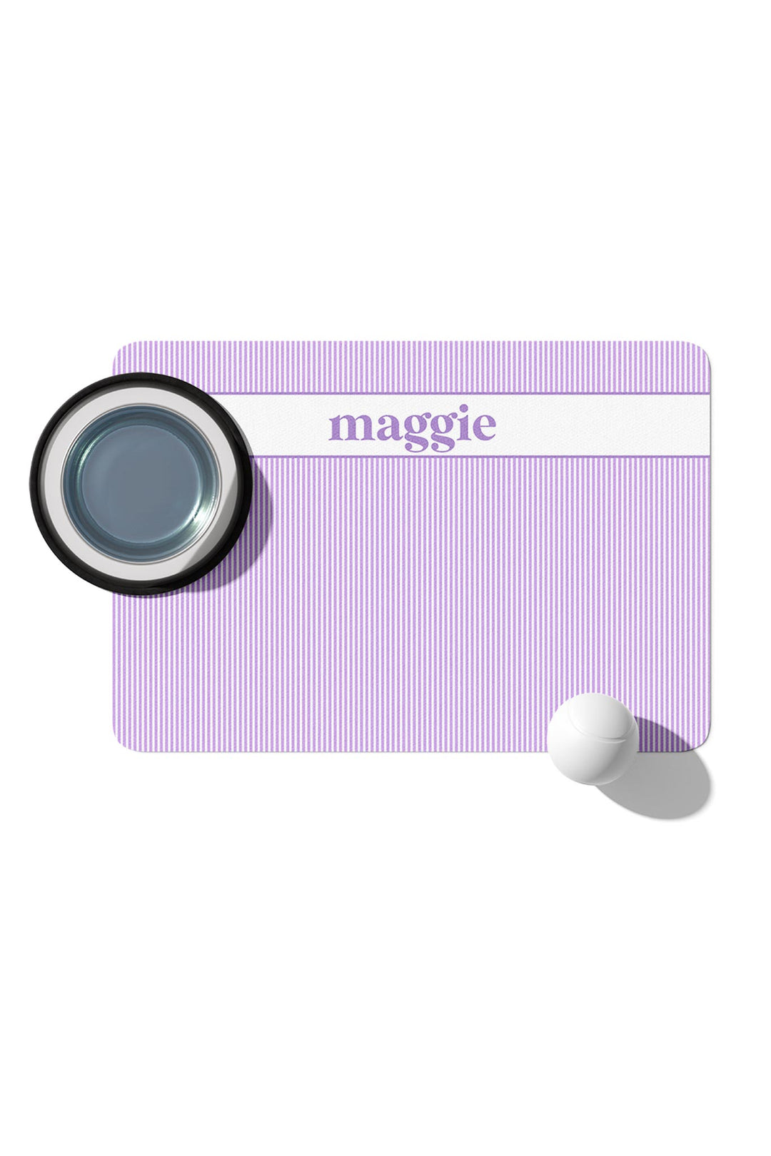 Personalized pet placemat in lavender and white stripes with a white banner and the name maggie in purple script, shown with a dark pet bowl on top
