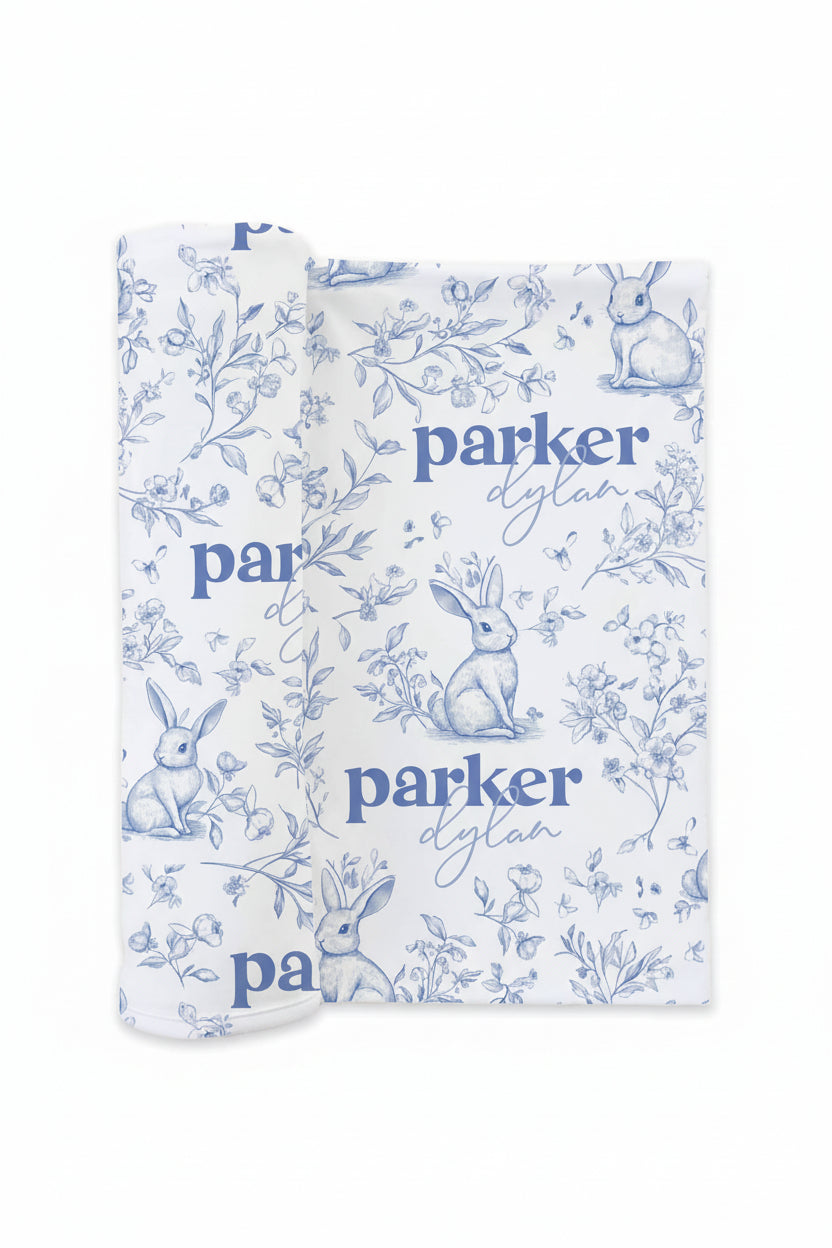 printed newborn baby swaddle with vintage style rabbit, flower sketches, blue outlines and personalized name 