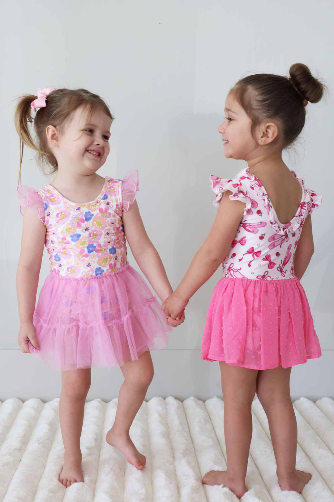 two girls looking at each other wearing leotards