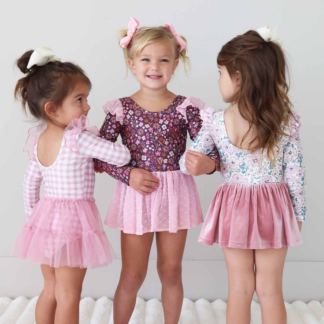 three girls interlocking arms wearing long sleeve leotards