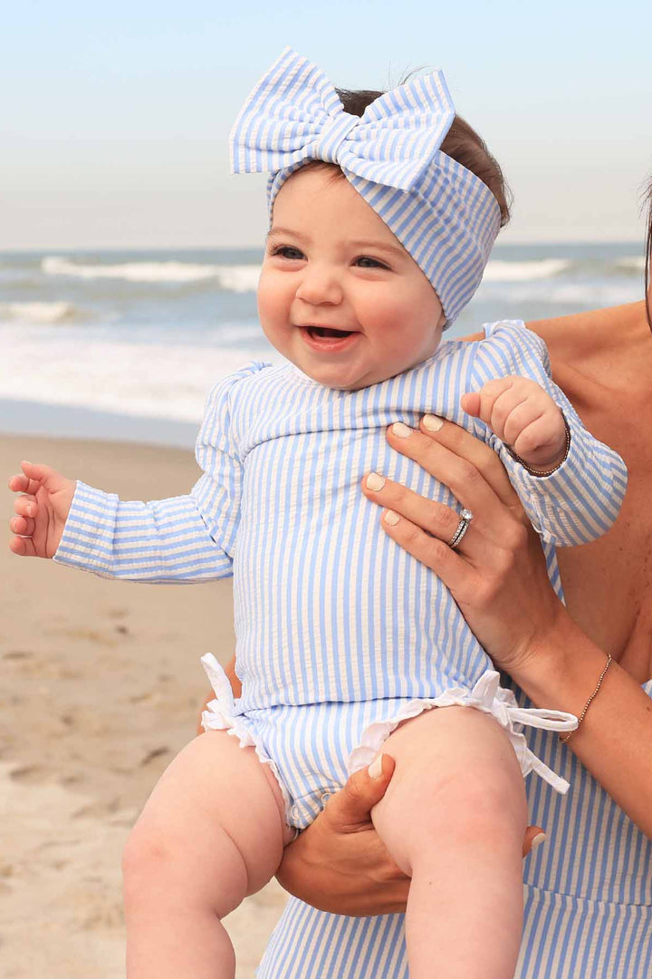 baby girl’s long sleeve rash guard swimsuit with ruffle bottom in seersucker blue with matching bow headwrap