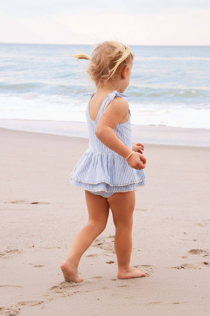 girls seersucker blue dress with tiered skirt and white pom pom trim