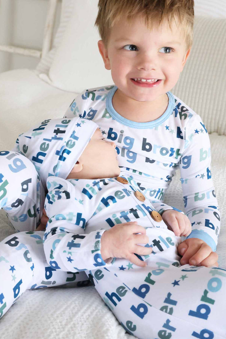 boy in big brother two-piece pajamas with newborn wearing little bother knot gown and hat matching set