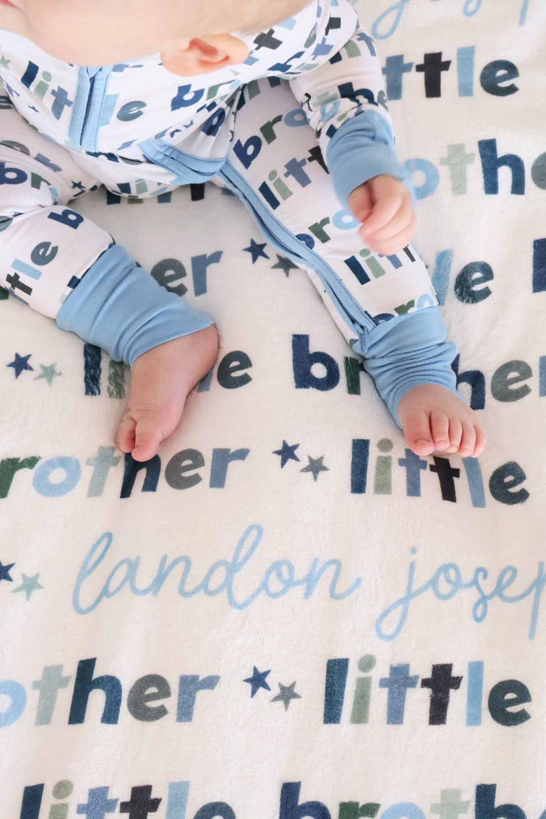 baby sitting on the little brother personalized blanket with matching zip romper