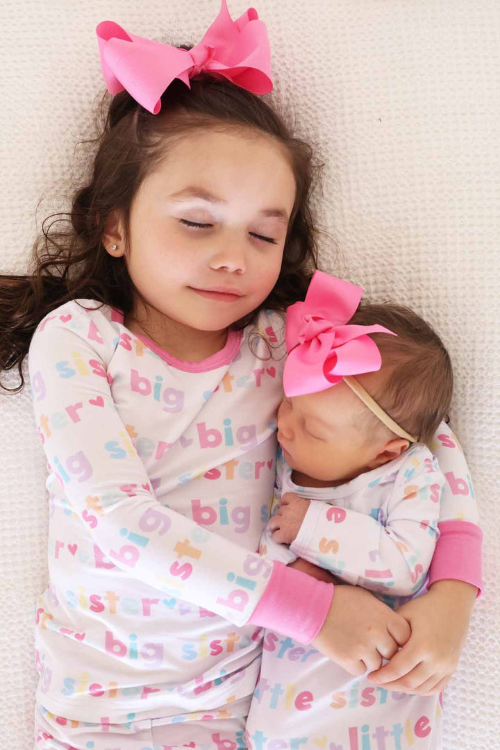 girl in big sister two piece pajama set and newborn wearing little sister knot gown