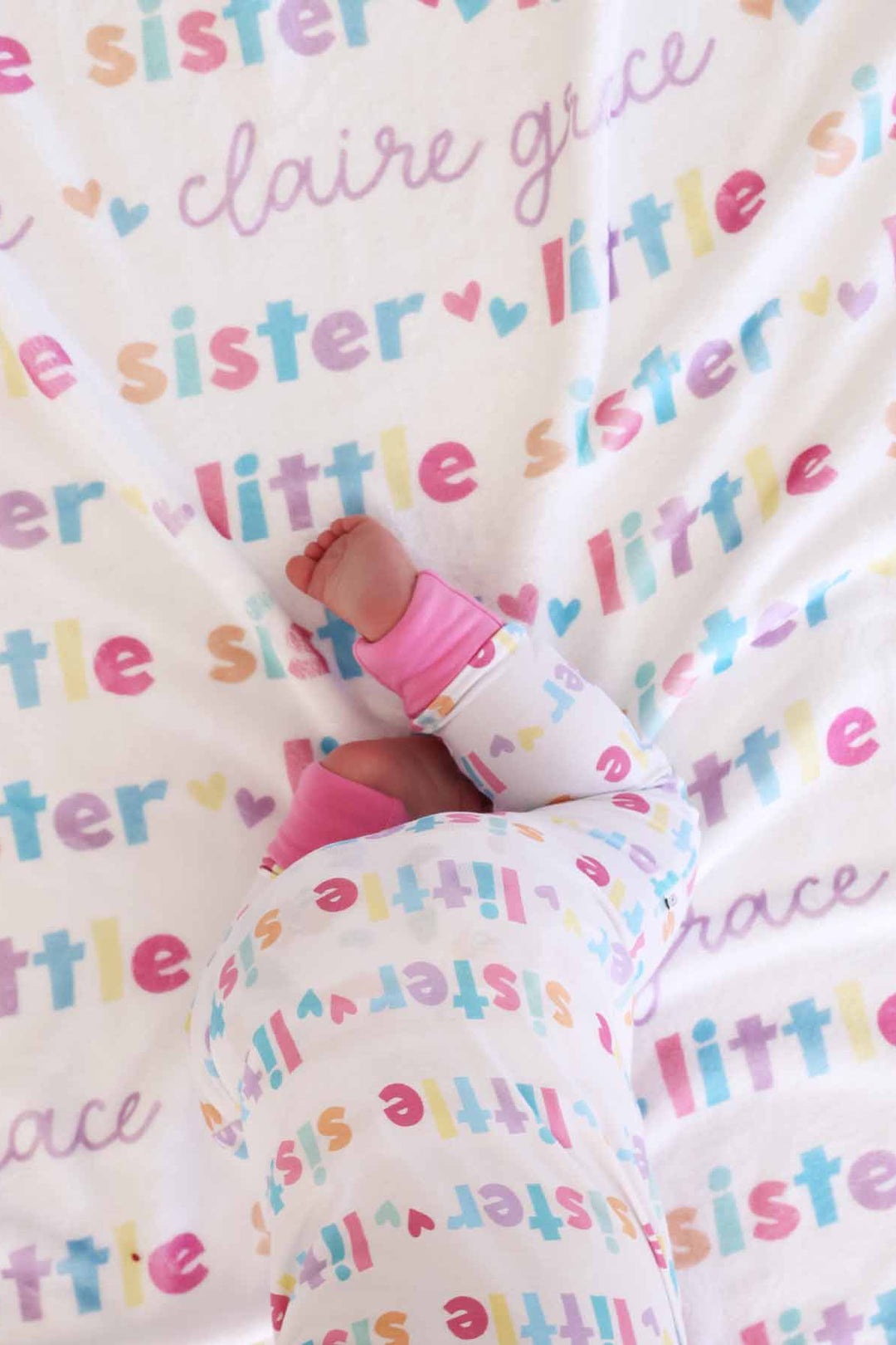 little girl crawling on the personalzied little sister blanket and wearing matching zip romper