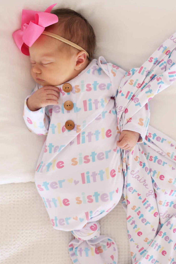 newborn wearing little sister knot gown with personalized swaddle