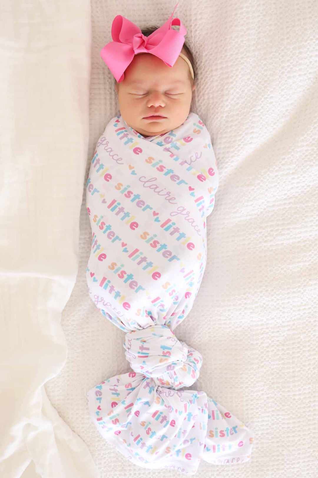 newborn wearing little sister personalized swaddle