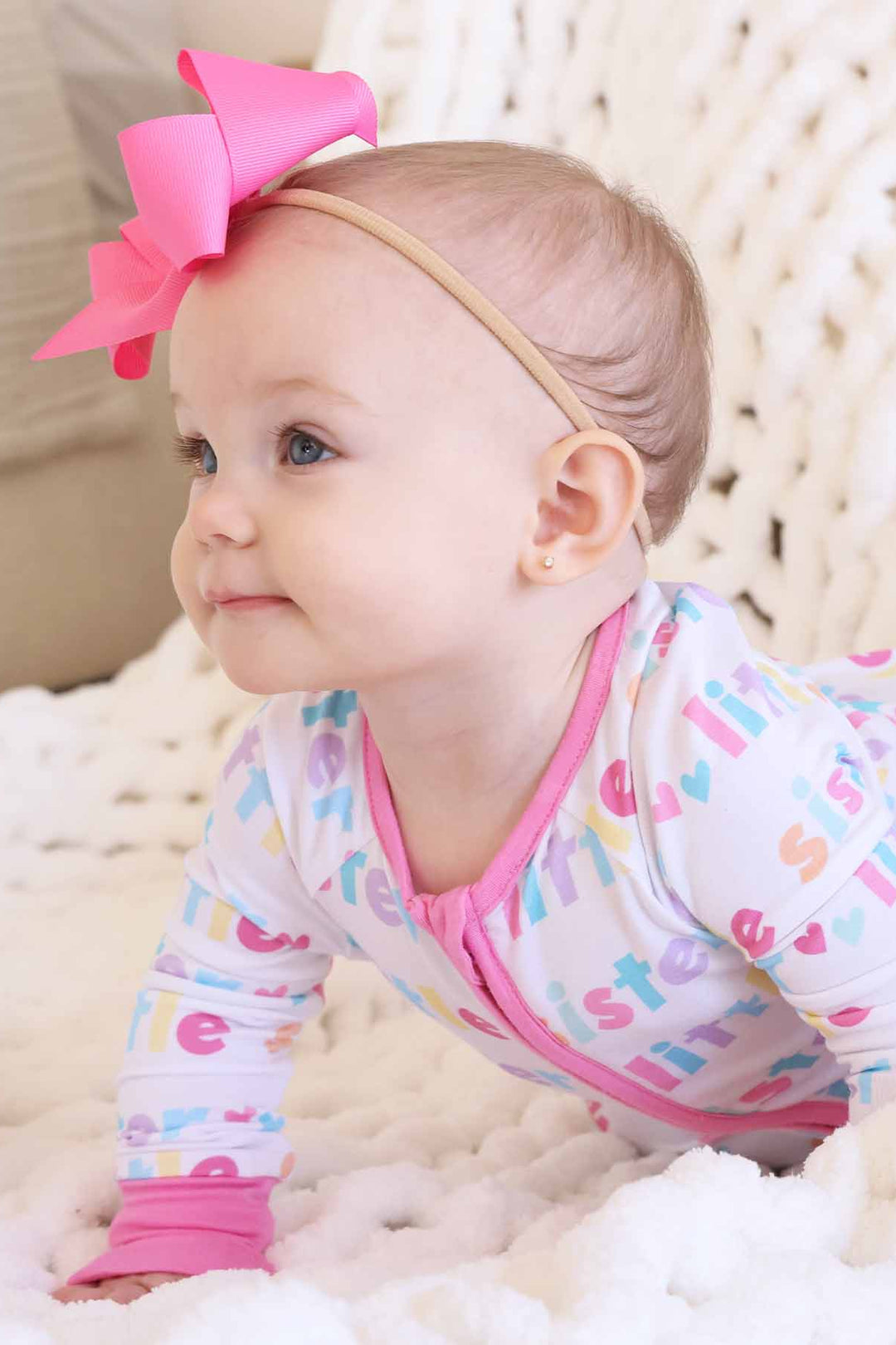 baby girl wearing little sister zip romper and pink bow headband