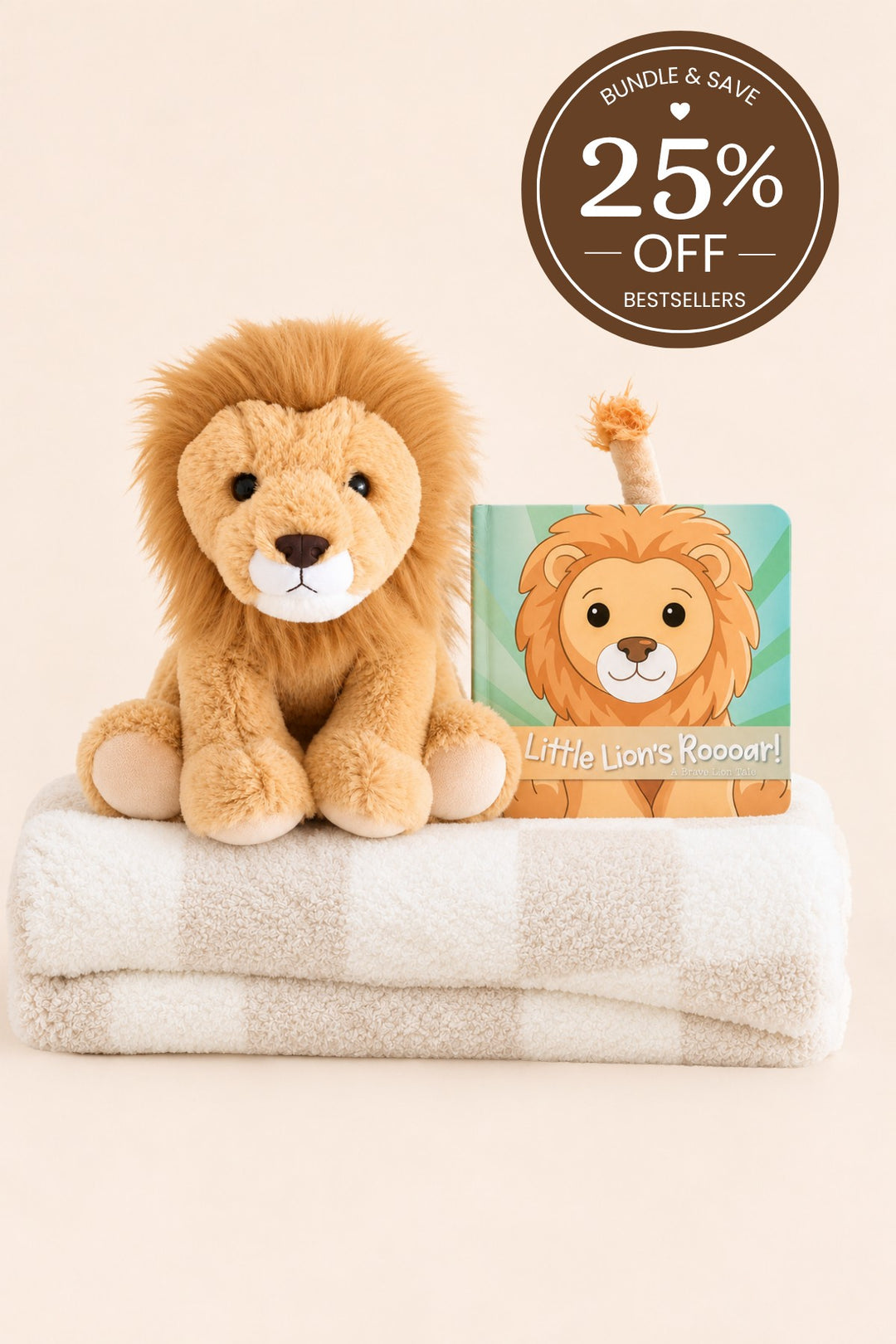 A Caden Lane plush lion seated on a folded cream-and-tan striped blanket, paired with a matching lion board book.
