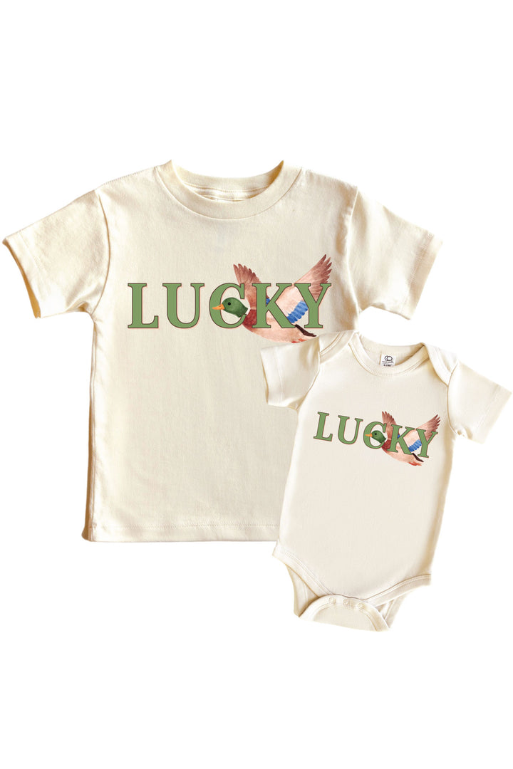 Natural Lucky Duck graphic kids tee and baby bodysuit displayed together, each with LUCKY text and mallard duck illustration on front