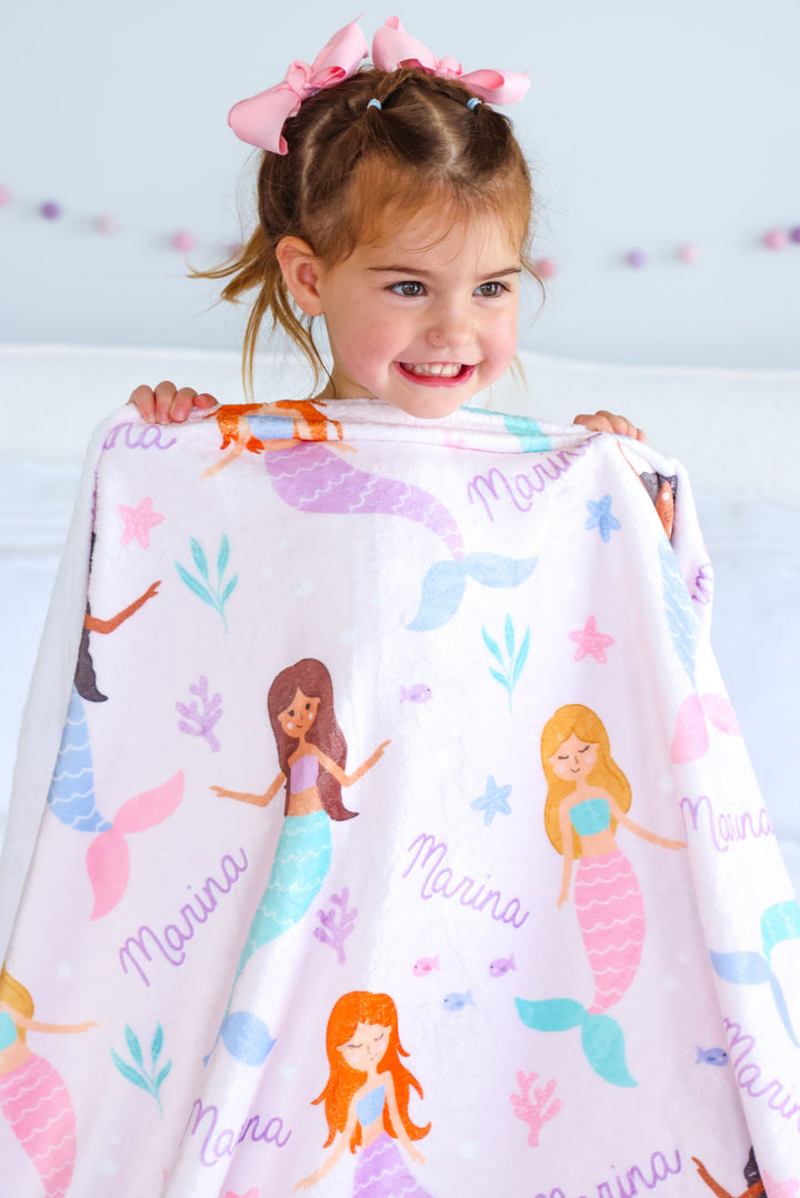 child snuggling with let's be mermaids personalized blanket
