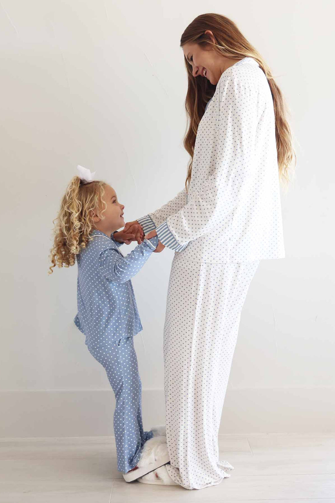 girl standing on her mom's feet wearing a long sleeve flare pants lounge sets with polka dots in inverted colors: dusty blue and white 