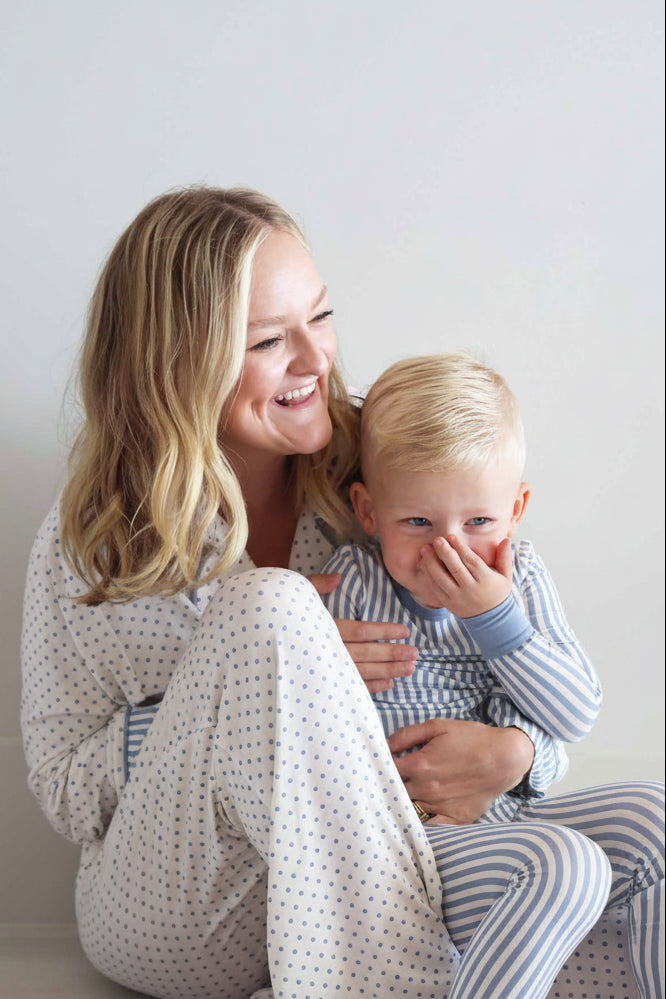 woman wearing a long sleeve lounge set white with blue polka dots with son on her lap in coordinating pajama set with blue and white stripes 