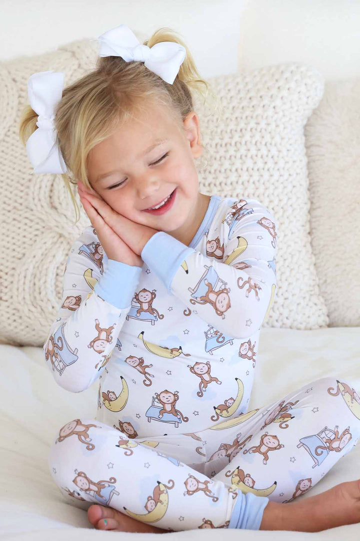 girl wearing pajamas with monkeys jumping on a bed and sleeping on banana moons