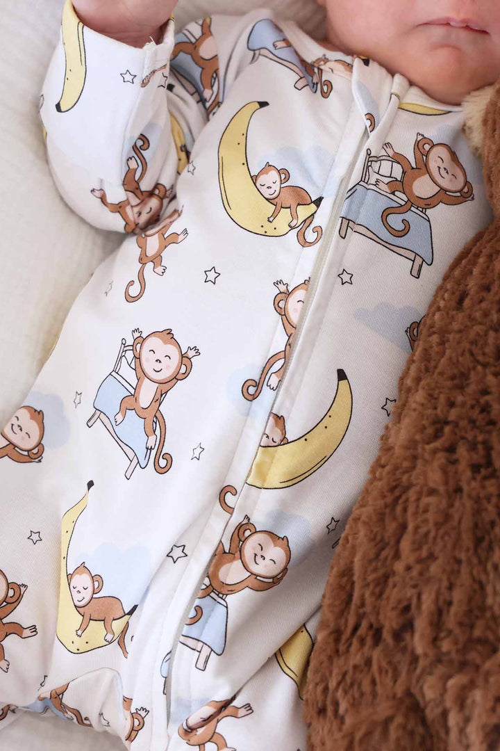 sleeping money on bed and banana moon with stars in the background bamboo zipper footie for babies 