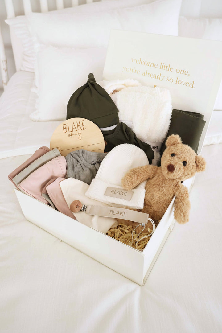 baby shower gift box bundle with neutral earthy tone pajamas, blanket, bear stuffed toy, burps and bibs