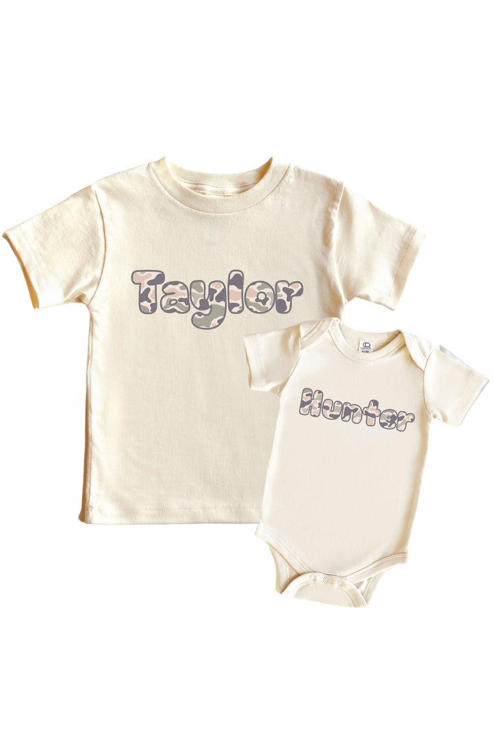 Natural cream kids graphic tee and baby bodysuit with personalized camo-print name graphic side by side